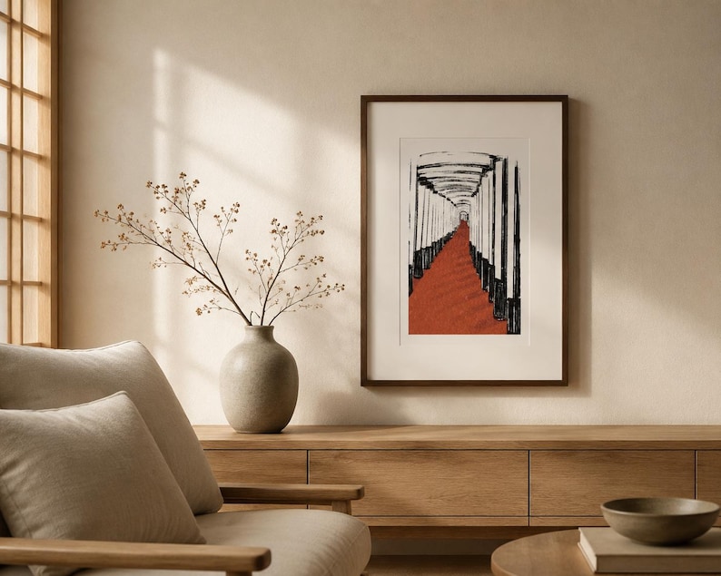 May include: A framed wall art print featuring a black and white ink-style illustration of a path lined with vertical pillars leading toward a bright opening, set against a textured terracotta-colored ground, displayed in a dark brown frame.