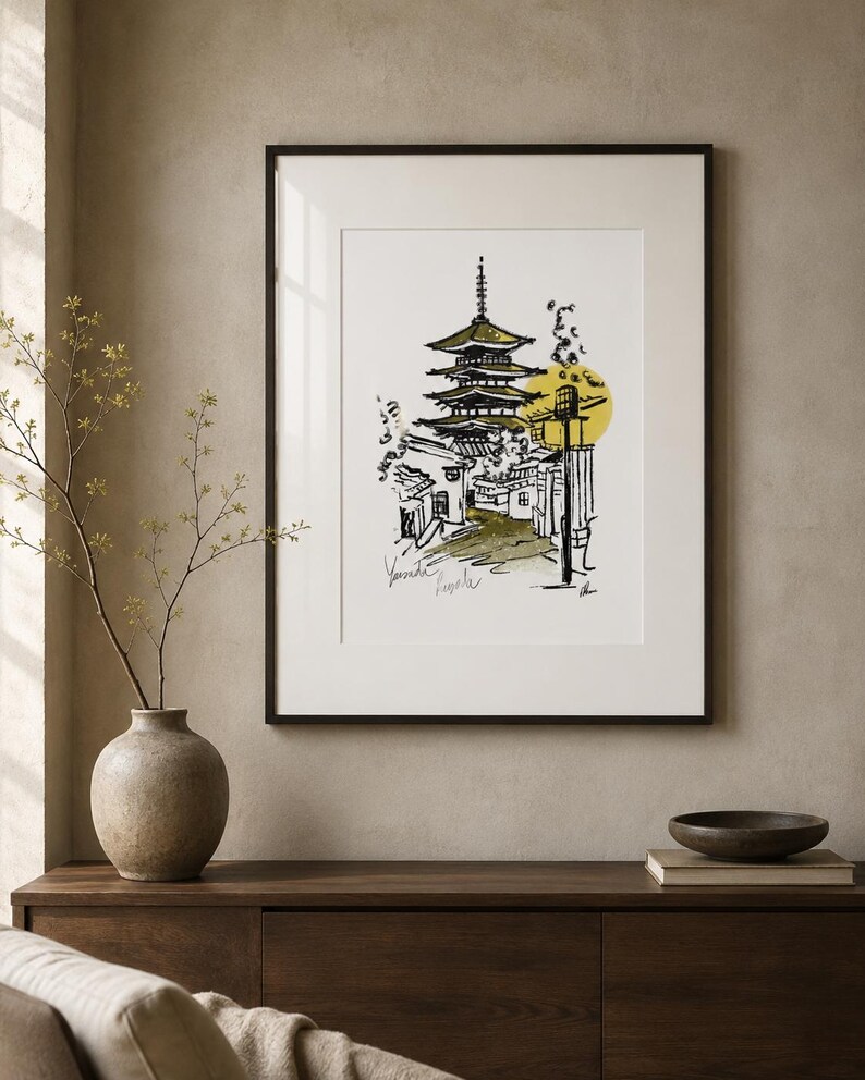 Puede incluir: Una l&aacute;mina art&iacute;stica enmarcada que presenta un boceto en tinta negra de una pagoda de varios niveles y edificios circundantes. La ilustraci&oacute;n incluye un acento circular amarillo y texto escrito a mano en la parte inferior izquierda, todo en un marco negro.