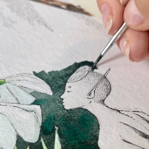 May include: Watercolor painting in progress, depicting a serene scene with a figure and stylized flora. The figure has a detailed, dotted design on the head and ear. The artist's hand holds a brush, adding details to the artwork. The color palette includes white, green, and black.