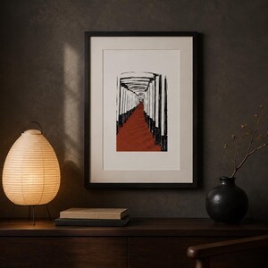 May include: A framed vertical art print featuring a black and white illustration of a tunnel of pillars with a deep red path. The artwork is displayed in a black frame with a white mat, positioned above a wooden surface with a lamp and vase.