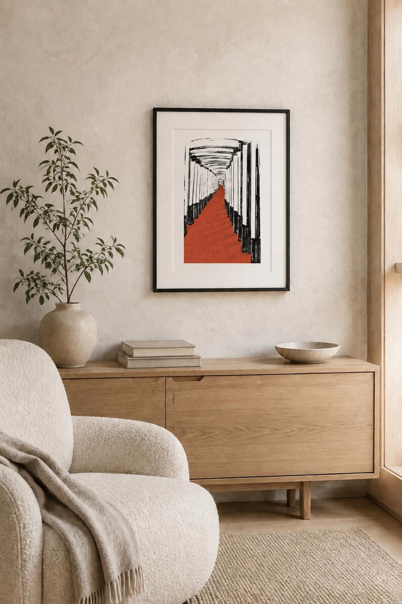 May include: A framed wall art print featuring a black and white ink-style illustration of a long corridor with a vibrant red floor. The artwork is enclosed in a thin black frame with a white mat border, displayed on a neutral-toned wall.