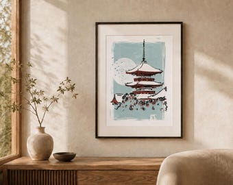 May include: A framed wall art print featuring a multi-tiered pagoda in shades of red and white against a light blue background. A large white circular moon is visible behind the structure, with dark floral elements at the base of the pagoda.