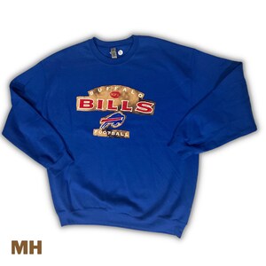 Op de afbeelding: Blauw sweatshirt met een vintage Buffalo Bills logo. Het logo is bruin en goud met rode letters en toont het team mascotte, een buffel.