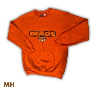 May include: Orange sweatshirt with a camouflage print "BEARS" graphic and a Chicago Bears logo.