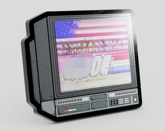 May include: A dark gray enamel pin shaped like a vintage television set. The screen displays a stylized American flag background with the text G.I. JOE A REAL AMERICAN HERO. The frame features detailed black line work and control panel buttons.