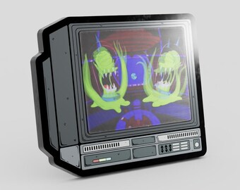 May include: A dark gray, rectangular enamel pin shaped like a vintage television set. The screen displays two bright green, tentacled alien creatures with sharp teeth. The television frame features detailed control panels, buttons, and vents.