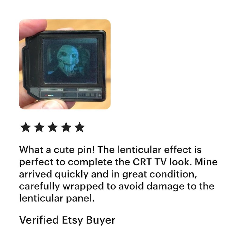 May include: A black pin shaped like a retro television set, featuring a lenticular image of a character. The pin is held by a hand. The image on the screen appears to be a character from a horror movie.