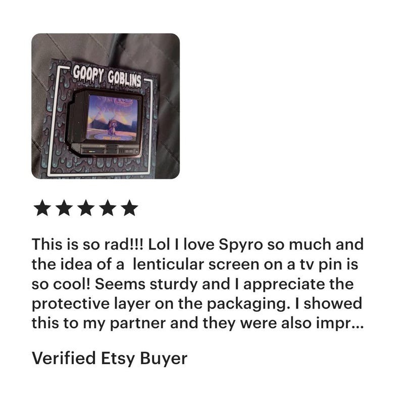 May include: A pin featuring a miniature television with a lenticular screen displaying a video game scene. The pin is labeled "GOOPY GOBLINS" and is set on a patterned background. The image includes a customer review.