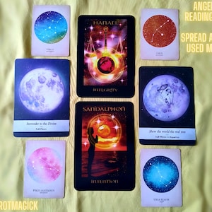 May include: A spread of angel cards with celestial imagery, including constellations, moons, and a figure with wings. The cards are arranged in a circle with the text "ANGEL CARD READING SAMPLE" and "SPREAD AND DECKS USED MAY VARY" at the top.