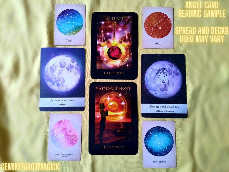 May include: A spread of angel cards with celestial imagery, including constellations, moons, and a figure with wings. The cards are arranged in a circle with the text "ANGEL CARD READING SAMPLE" and "SPREAD AND DECKS USED MAY VARY" at the top.