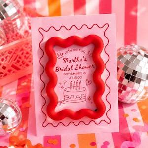 Op de afbeelding: Een lichtroze rechthoekige uitnodigingskaart met een rode golvende rand. De tekst luidt: JOIN US FOR Martha's Bridal Shower SEPTEMBER 18. AT 16:00. Onder de tekst staat een lijntekening van een taart met kaarsjes, hartjes en sterretjes.