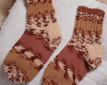 May include: A pair of brown and beige patterned knitted socks. The socks have a geometric design and are made of a soft, warm material.