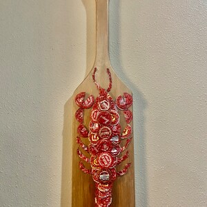 Bottle cap crawfish on wooden paddle board