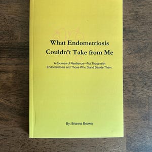 May include: A yellow book titled "What Endometriosis Couldn't Take from Me" by Brianna Booker. The book's subtitle reads "A Journey of Resilience - For Those with Endometriosis and Those Who Stand Beside Them."