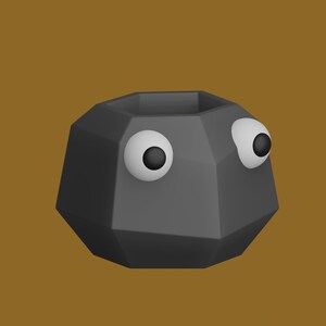 May include: A gray geometric planter with two large googly eyes. The planter is made of a smooth, matte material.