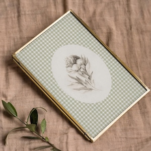 Pu&ograve; includere: Una cornice per foto in ottone con un motivo a quadri verdi e bianchi. La cornice contiene una stampa botanica in bianco e nero di un fiore.
