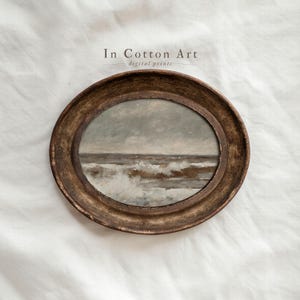 May include: An oval framed print of a seascape with a stormy sky and crashing waves. The frame is a distressed gold color. The text "In Cotton Art digital prints" is at the top.