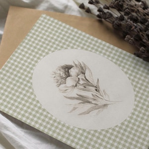 Pu&ograve; includere: Un biglietto di carta a quadri verdi e bianchi con un design circolare che presenta un'illustrazione in bianco e nero di un fiore.