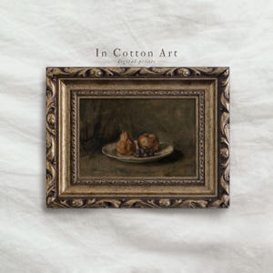 May include: A framed art print titled In Cotton Art featuring a still life painting of a pear, an apple, and a cluster of grapes on a plate. The frame is ornate, metallic gold with dark brown detailing, surrounding the dark-toned oil painting.