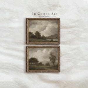 Op de afbeelding: Twee ingelijste landschapsschilderijen met een vintage esthetiek. Het kunstwerk toont een bewolkte lucht boven een veld met bomen en een waterpartij. De lijsten zijn versierd met een gouden afwerking. De tekst "In Cotton Art - digital prints" staat bovenaan.