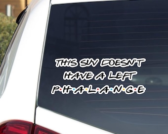 May include: A white car window sticker with the text "THIS SIN DOESN'T HAVE A LEFT PHALANGE" in a white font. The word "PHALANGE" is in the style of the TV show Friends, with each letter in a different color.