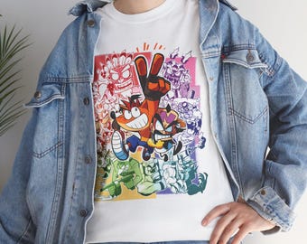 May include: White t-shirt with a colorful cartoon graphic of Crash Bandicoot and other characters from the video game series. The graphic features a variety of colors, including red, orange, yellow, green, blue, and purple.