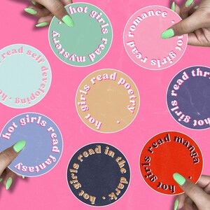 Pode incluir: Sete adesivos redondos coloridos com o texto "hot girls read" em um círculo ao redor da borda de cada adesivo. Cada adesivo tem um gênero de livro diferente escrito dentro do círculo. Os gêneros são: mistério, desenvolvimento pessoal, poesia, thrillers, fantasia, dark academia e mangá.