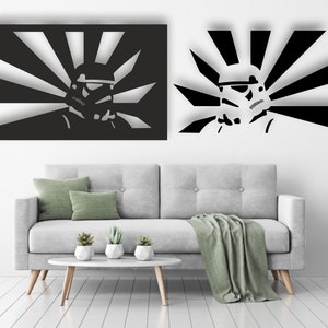 May include: A black and white wall decor featuring a stylized image of a Stormtrooper helmet with a rising sun behind it. The decor is shown hanging on a white wall above a gray couch.