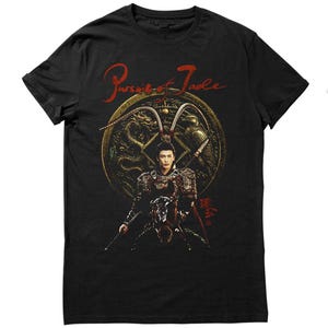 May include: Black t-shirt with a detailed graphic of a person in ornate armour, holding a weapon, with a golden emblem. The text "Pursuit of Jade" is written in red script above the graphic.