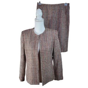 May include: A brown, white, and orange tweed skirt suit with a jacket and a skirt. The jacket has a round neckline and long sleeves. The skirt is knee-length.