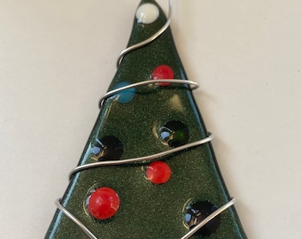 May include: A triangular dark green glass ornament with a subtle glitter finish, decorated with small, raised circular accents in red, blue, black, and white. A silver-toned metal wire is wrapped around the glass in a spiral pattern.