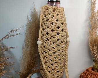 Puede incluir: Un porta botellas de crochet beige con una correa larga y cuentas de madera. El porta botellas está diseñado para adaptarse a una botella de agua reutilizable.
