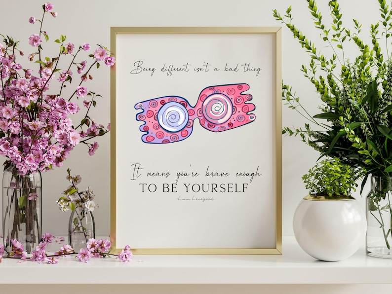 Puede incluir: Una impresi&oacute;n enmarcada en dorado con una ilustraci&oacute;n rosa y morada de un par de gafas. El texto de la impresi&oacute;n dice "Ser diferente no es algo malo. Significa que eres lo suficientemente valiente para SER T&Uacute; MISMO."
