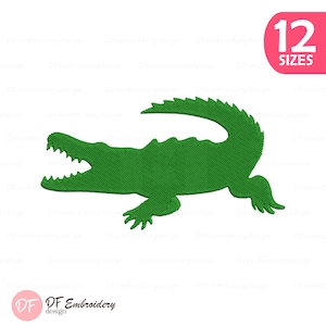 Pode incluir: Um desenho de jacaré verde com a boca aberta, texturizado com linhas diagonais. A imagem inclui um círculo rosa com o texto "12 TAMANHOS" e um logotipo que diz "DF Embroidery design".