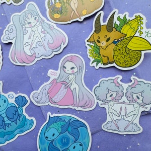 K&ouml;nnte beinhalten: Ein Set mit 10 bunten Stickern mit Sternzeichen. Jeder Sticker hat ein einzigartiges Design mit einer Comicfigur und einem astrologischen Symbol. Die Sticker eignen sich perfekt zum Dekorieren von Laptops, Wasserflaschen, Tageb&uuml;chern und vielem mehr.