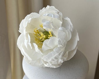 May include: A white ceramic vase with a textured surface. The vase is stacked in a graduated size and has a white peony flower on top.