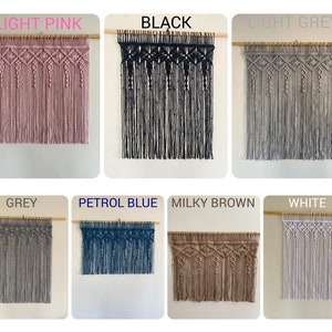 May include: A collection of eight macrame wall hangings in various colors, including light pink, black, light grey, grey, petrol blue, milky brown, and white. Each hanging features a geometric pattern with a wooden dowel at the top.