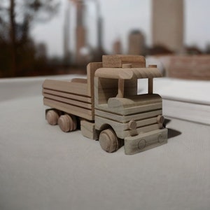 May include: A wooden toy truck with a flatbed and four wheels. The truck is made of light brown wood and has a simple design.