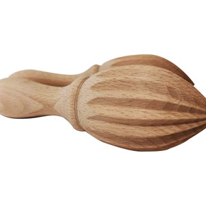 May include: A wooden citrus juicer with a ribbed design. The juicer is made of light brown wood and has a handle on one end.