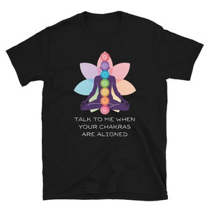 Puede incluir: Camiseta negra con un símbolo de chakra colorido y el texto "Háblenme cuando sus chakras estén alineados".