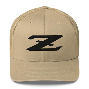 May include: Tan trucker hat with a black stylized "Z" logo on the front. The hat features a mesh back and a curved brim. The hat is a neutral color and suitable for various outfits.