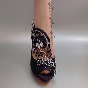 Peut inclure: Chaussures &agrave; talons noirs en satin avec une embellissement en dentelle noire et strass.