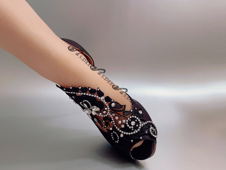 Peut inclure: Chaussures &agrave; talons noirs en satin avec une embellissement en dentelle noire et strass.