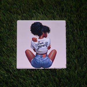 May include: Square print featuring a woman with dark skin and curly hair, wearing a white t-shirt and denim shorts. The shirt has the words "Love Yourself" in cursive. The woman is embracing herself. The print is on a white background.