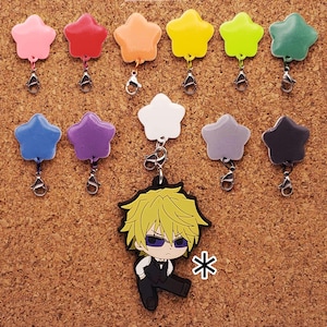 May include: A collection of colourful star-shaped charms with a cartoon character charm of a blonde-haired man wearing a black suit and a white shirt. The charms are attached to silver jump rings.