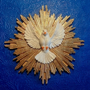 Könnte beinhalten: Eine weiße Taube mit ausgebreiteten Flügeln ist auf einem goldfarbenen Strahlenmuster zentriert. Die Taube hat orangefarbene Füße und einen Schnabel. Der Hintergrund ist eine strukturierte, tiefblaue Oberfläche.