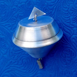 May include: A silver-colored metal spinning top with a triangular accent on top. The top has a conical shape with a rounded base and a small, cylindrical handle attached to the bottom.