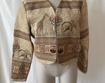 May include: A beige cropped jacket with a brown and tan patterned design featuring elephants and giraffes. The jacket has a V-neck and a button closure.