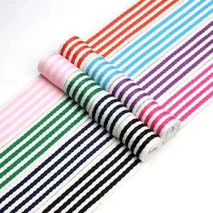 May include: A collection of striped ribbon in various colors, including pink, green, navy, black, light blue, purple, and red. The ribbon is rolled up and arranged in a fan shape.