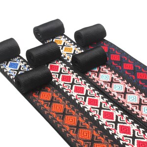 Peut inclure: Cinq galons tiss&eacute;s noirs avec des motifs g&eacute;om&eacute;triques color&eacute;s. Les motifs comprennent du rouge, du bleu, de l'orange, du rose et du blanc.